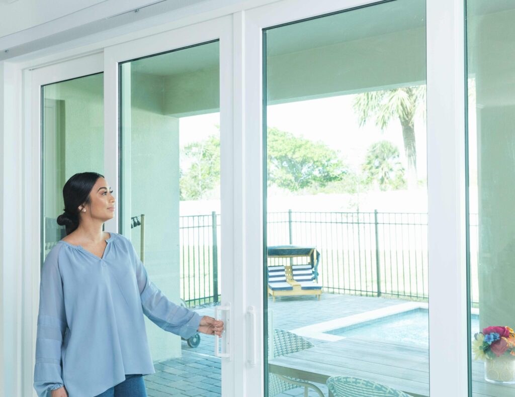 Homeowner opening sliding glass patio doors installed by Wallaby Windows, creating seamless indoor-outdoor living and maximizing natural light
