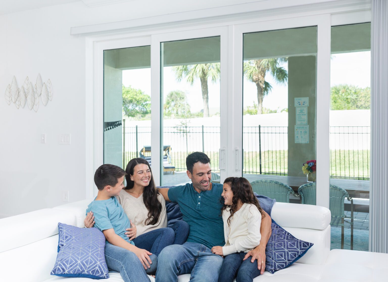 Family relaxing on couch in front of large sliding glass doors, enjoying natural light and energy-efficient window installation by Wallaby Windows