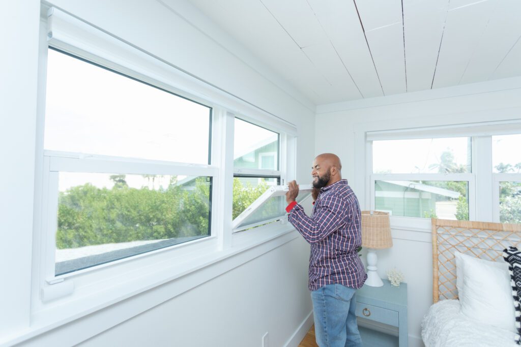 Homeowner opening a horizontal awning window from Wallaby Windows, demonstrating easy operation, fresh airflow, and modern interior comfort