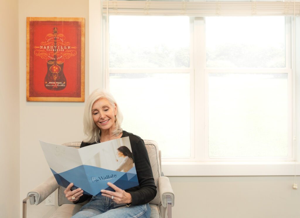 Homeowner relaxing by a bright replacement window from Wallaby Windows while reviewing product options, showcasing natural light and energy-efficient design