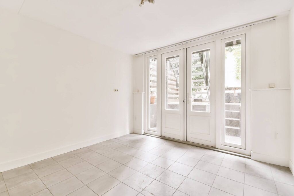 Minimalist living space with large glass patio doors, tiled flooring, and soft daylight highlighting indoor-outdoor connection