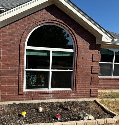 Modern arched window with grid design installed on brick exterior for enhanced style and performance