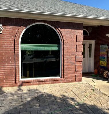 Upgraded arched window installation with modern glass improving curb appeal and energy efficiency on brick home