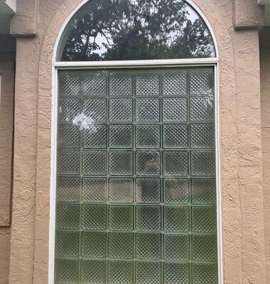 Original arched glass block window before replacement on stucco exterior
