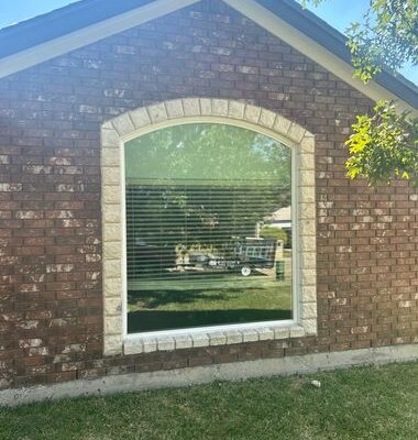 Upgraded arched picture window installation improving curb appeal and energy efficiency on brick home