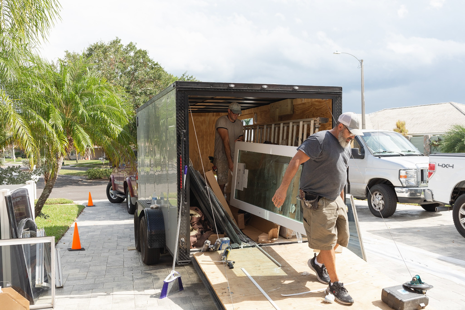 Wallaby Windows crew unloading replacement windows from trailer at residential job site, preparing for professional window installation