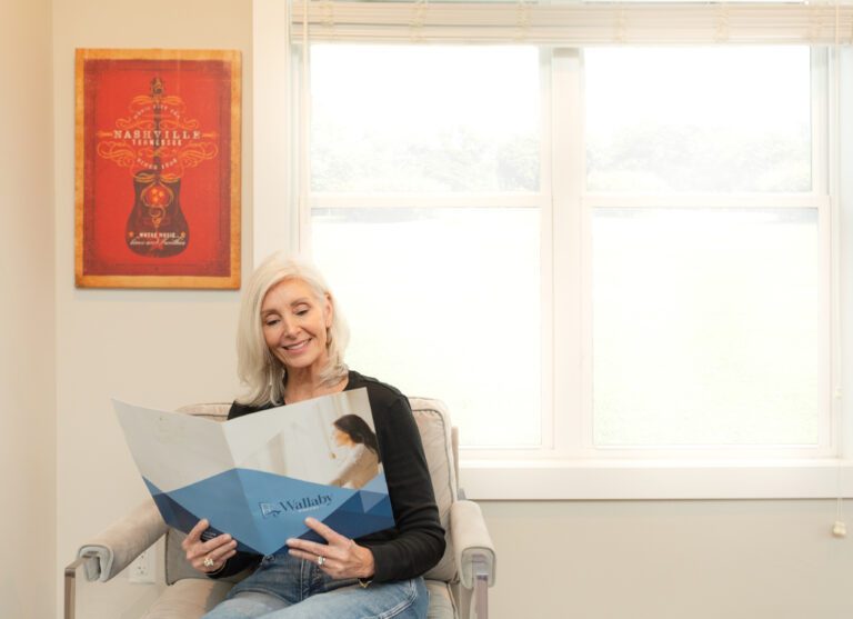 Happy homeowner reviewing Wallaby Windows materials in a bright living space, highlighting a smooth, stress-free window replacement experience and customer-focused service