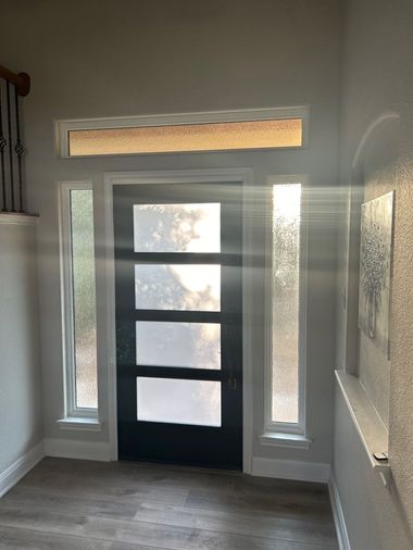 Modern front door with frosted glass panels, sidelights, and transom window professionally installed by Wallaby Windows for improved light and energy efficiency