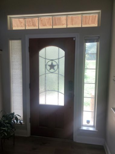 Front entry door with decorative glass, sidelights, and transom window installed by Wallaby Windows to enhance natural light and entryway design