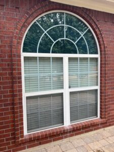 Red brick home with arched geometric window featuring white frame and grids